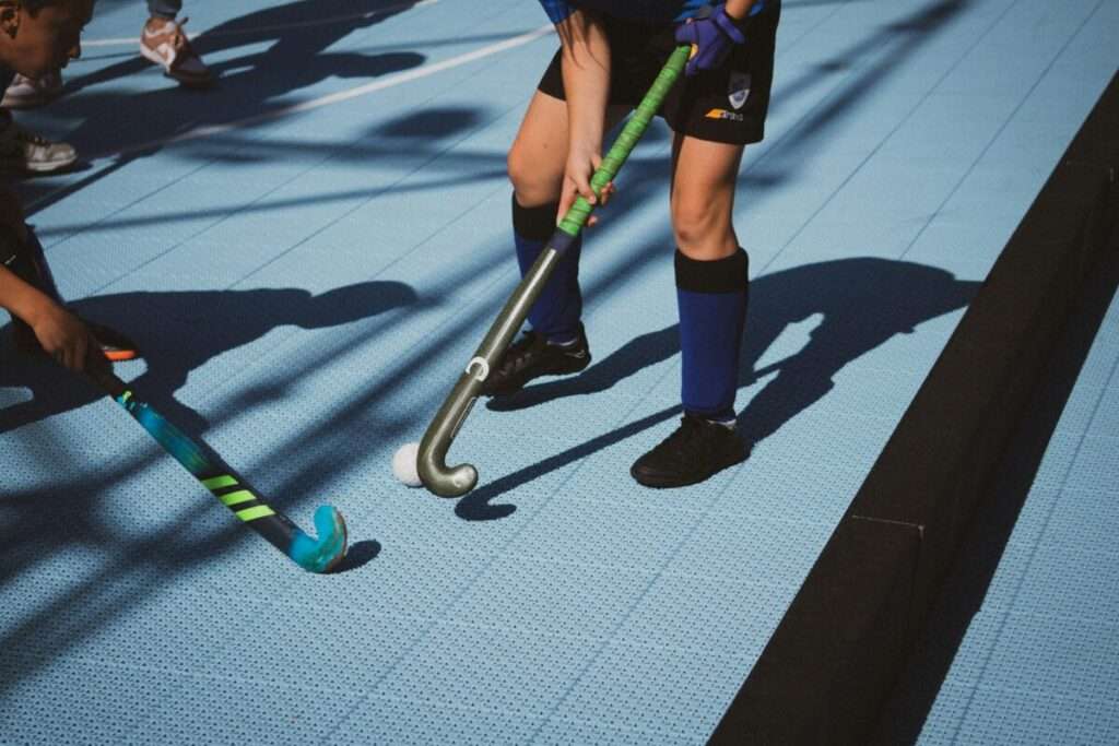 Hobby vs. Handy: Finde das beste Freizeitprojekt fürs Kind 3 Feldhockey Spieler mit Schläger als Beispiel für ein Hobby