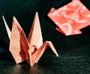 Close-up of a red origami crane with geometric patterns, highlighting delicate craftsmanship.