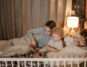Father and mother reading to their child in bed during nighttime for a cozy bedtime story.