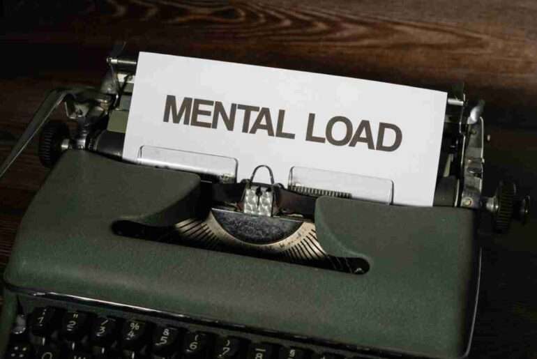 A vintage typewriter with a paper reading 'Mental Load', symbolizing stress and responsibility.