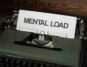 A vintage typewriter with a paper reading 'Mental Load', symbolizing stress and responsibility.